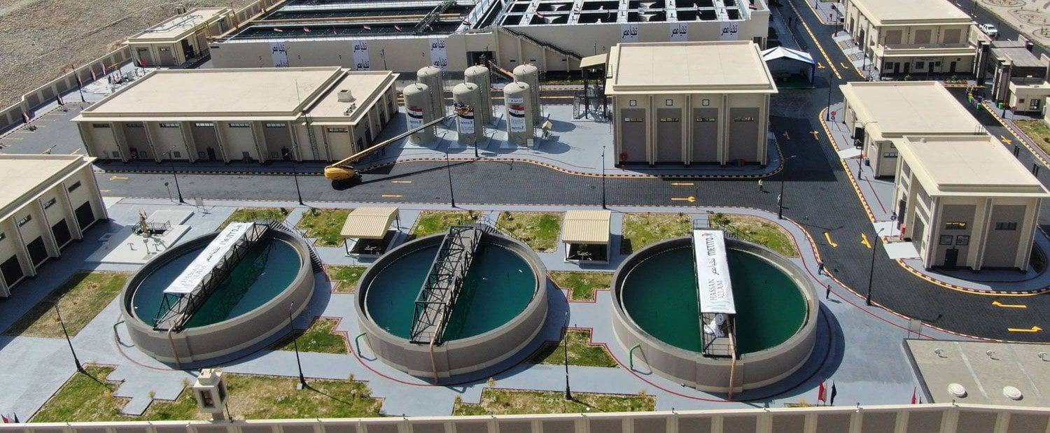 Aerial view of a UAE water treatment plant with circular clarifier tanks and process buildings.